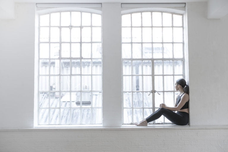Woman sitting on windowsill looking out of window